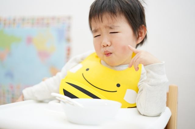 すっぱいものを食べて顔をしかめる子どもの顔