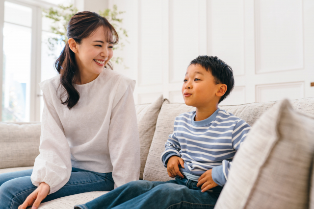 ソファーに座り笑顔で語り合う親子